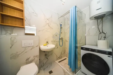 Bathroom with a shower cabin, washbasin, toilet, and washing machine. - image 2