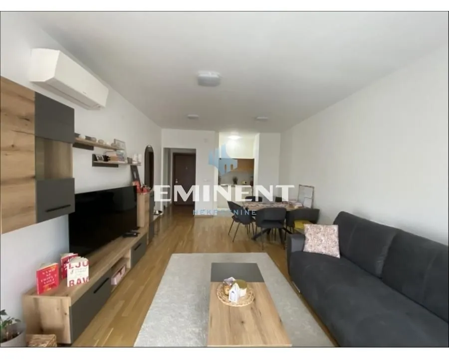 Living room with a sofa, TV, and dining area in the background.