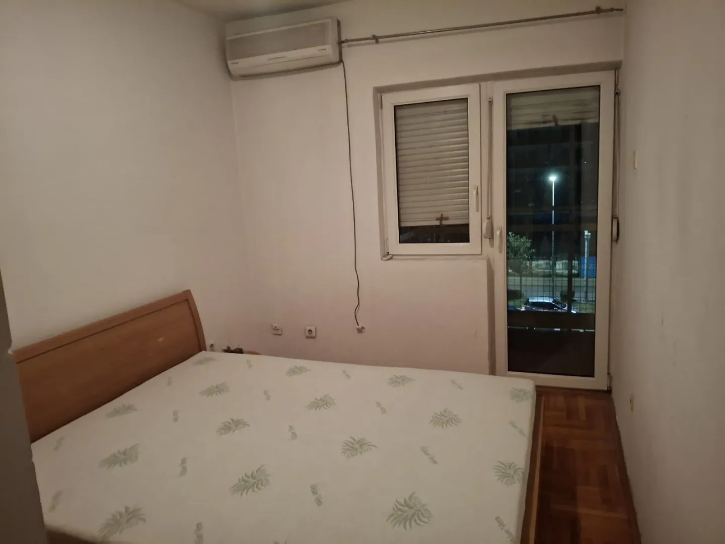 Spavaća soba sa bračnim krevetom, klima uređajem i izlazom na terasu.