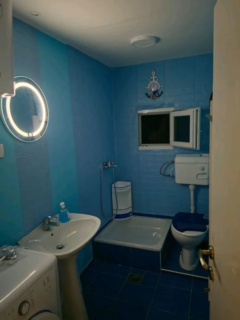 Small bathroom with blue walls, a sink, toilet, and a shower area.