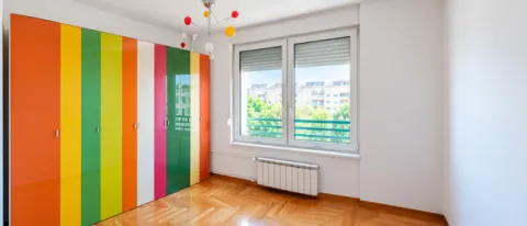 Children's room with a large colorful wardrobe, parquet flooring and a window. - image 2