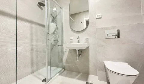 Moderno opremljeno kupatilo sa tuš kabinom, umivaonikom i toaletom u sivim tonovima. - image 4