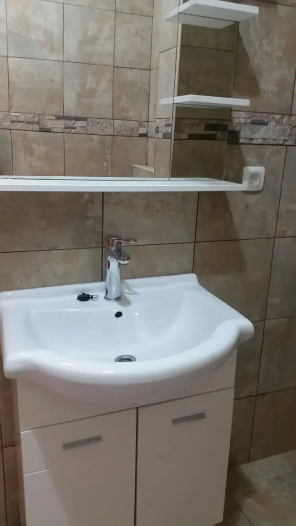 Bathroom sink with a white cabinet and a mirror.