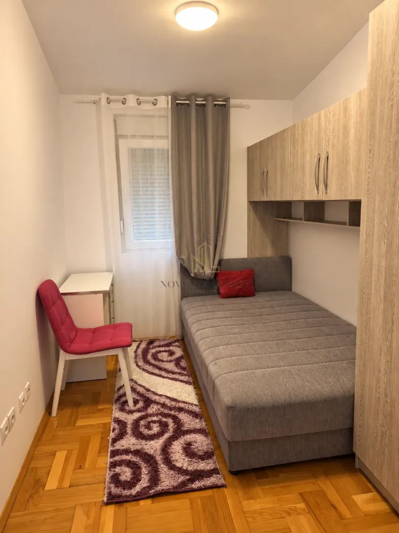 Smaller bedroom with a bed, wardrobe, desk and window.
