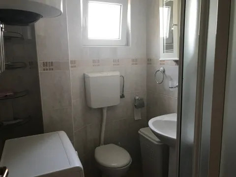 Compact bathroom with a sink, toilet, shower cabin, and washing machine. - image 9
