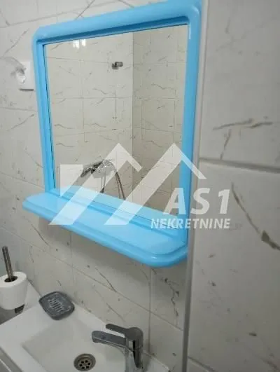 View of the sink and a mirror with a blue frame in the bathroom.