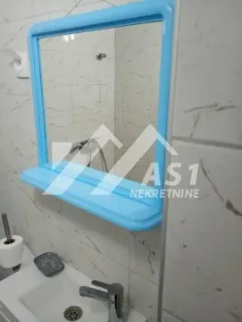 View of the sink and a mirror with a blue frame in the bathroom. - image 8
