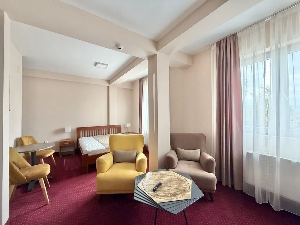 Spacious room with a bed, armchairs, and a carpet.
