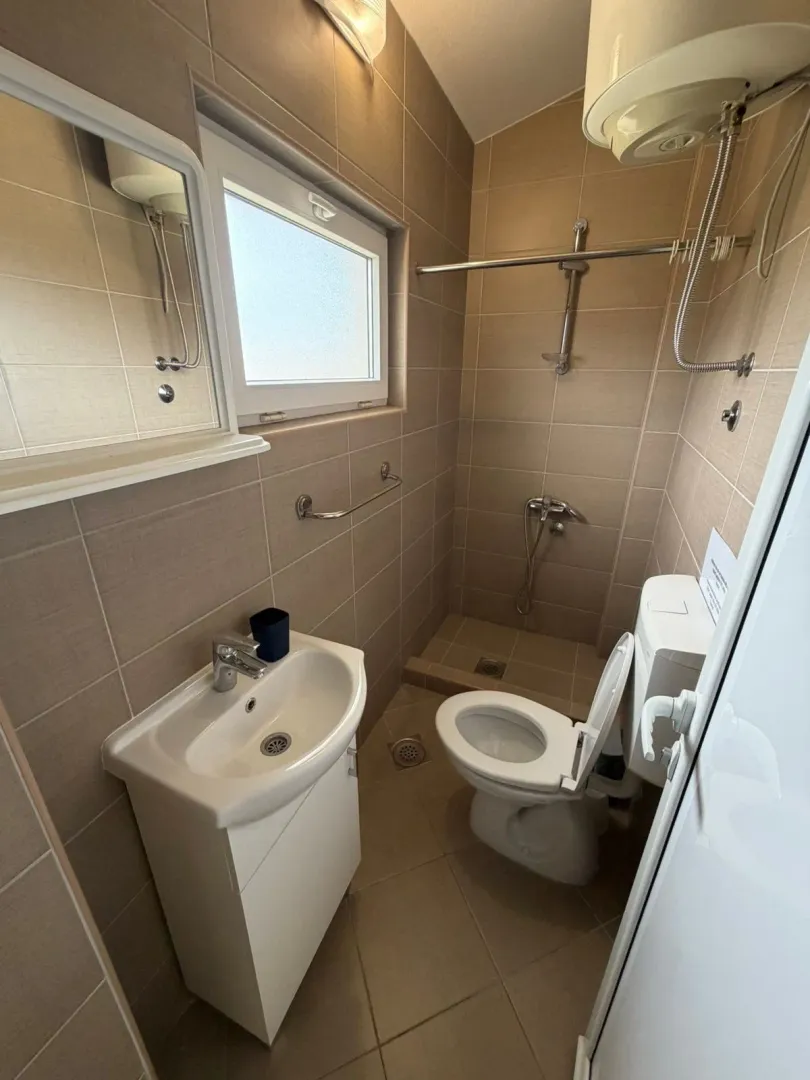 Smaller bathroom with a shower cabin, washbasin, and toilet.
