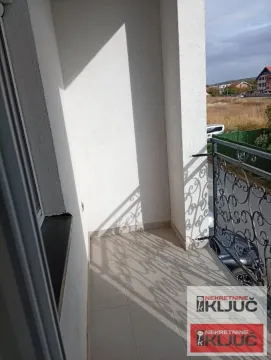 Pogled na namešten balkon sa metalnom ogradom i pogledom na okolinu. - image 11