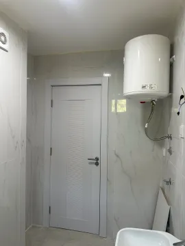 Kupatilo obloženo keramičkim pločicama sa ugrađenim bojlerom i vratima. - image 14
