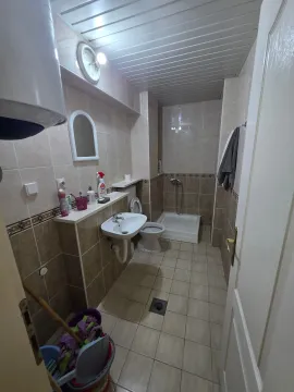 Manje kupatilo sa tuš kabinom, umivaonikom i WC šoljom u bež pločicama. - image 9