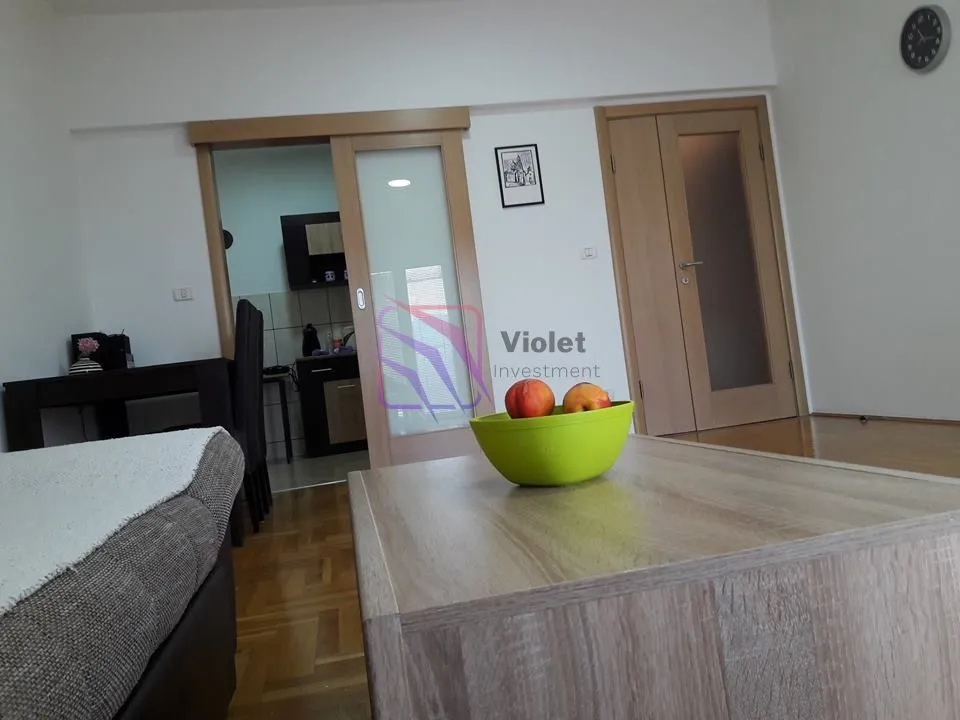Pogled na dnevni boravak sa garniturom, stočićem i drvenim vratima.