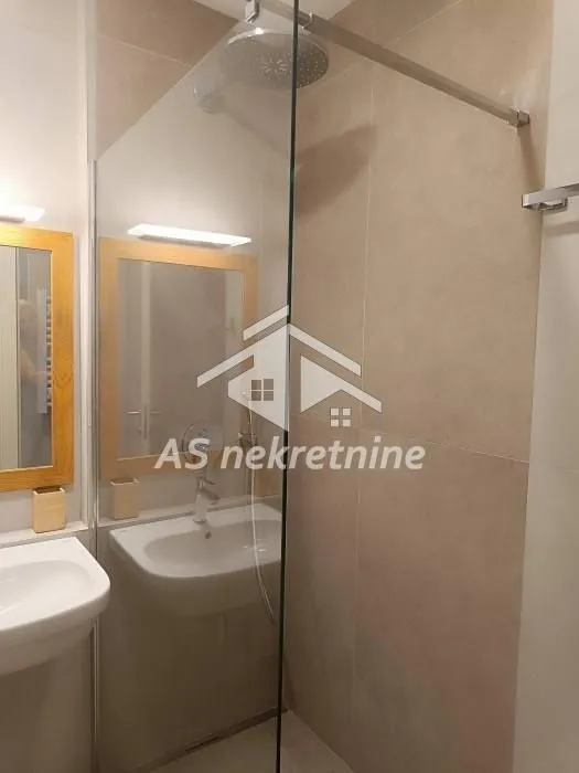 Moderno kupatilo sa tuš kabinom i umivaonikom.