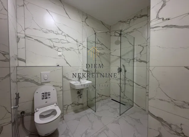 Modern bathroom tiled with marble finish and a walk-in shower.