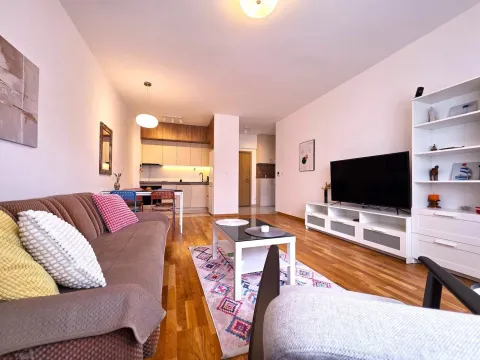 Living room with a sofa, TV unit, and open-plan dining area. - image 4
