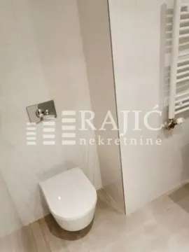 View of a modern bathroom with a wall-hung toilet and a towel radiator. - image 8