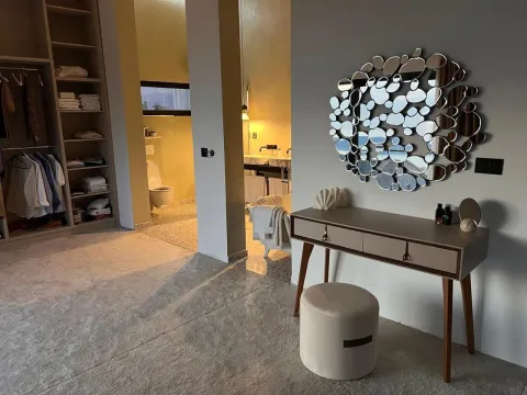 Modern bedroom with a walk-in wardrobe, vanity table, and a view of the bathroom. - image 9