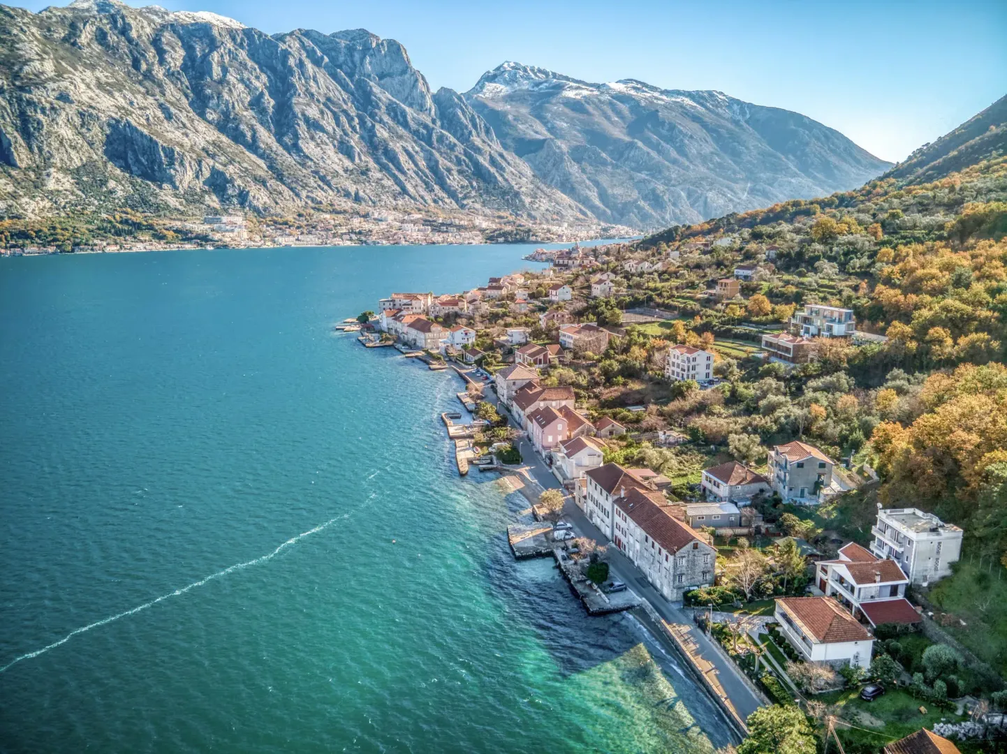 Aerial view of the bay and coastal settlement with a mountain range in the background.