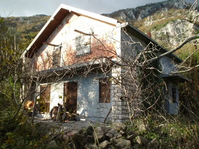 Nedovršena kuća okružena prirodom ispod planine.