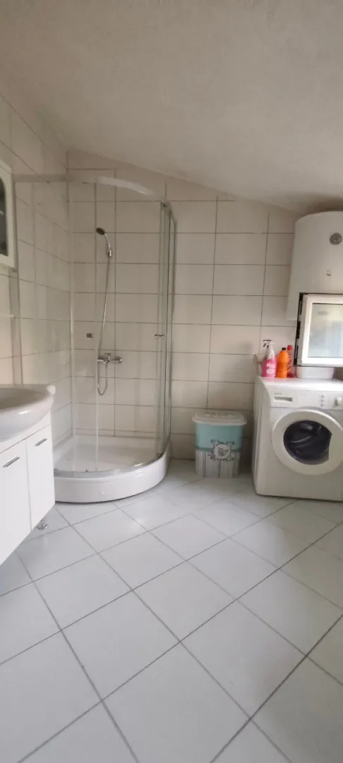 Bathroom equipped with a shower cabin, washbasin, and washing machine.