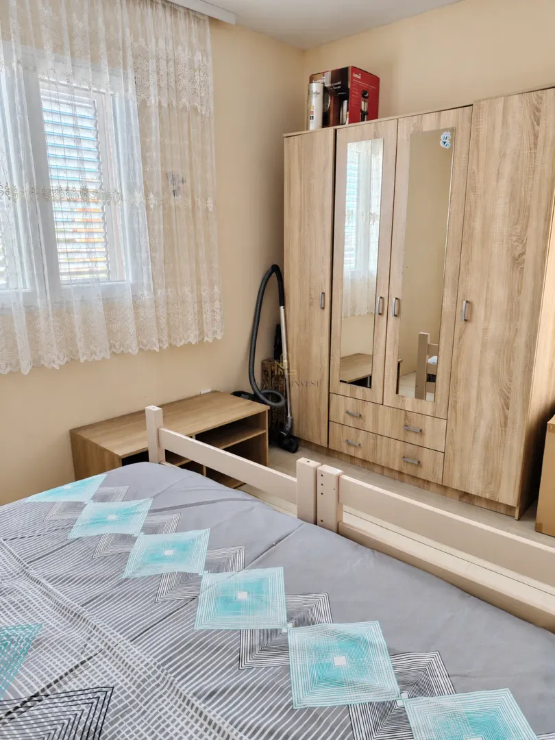 Furnished bedroom with a double bed, large wardrobe, and a window.