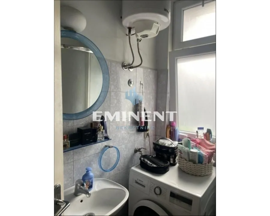 View of the bathroom with a washbasin, mirror, water heater, and washing machine.