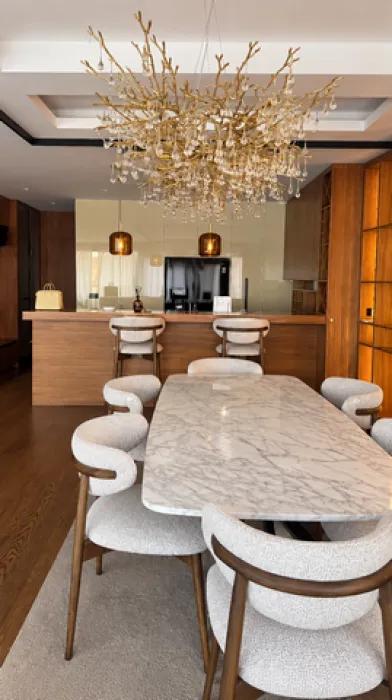 Dining area with a marble table and a modern chandelier.