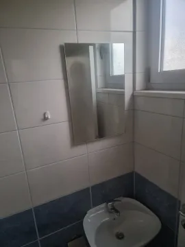 Manje kupatilo sa umivaonikom, ogledalom i pločicama na zidovima. - image 22