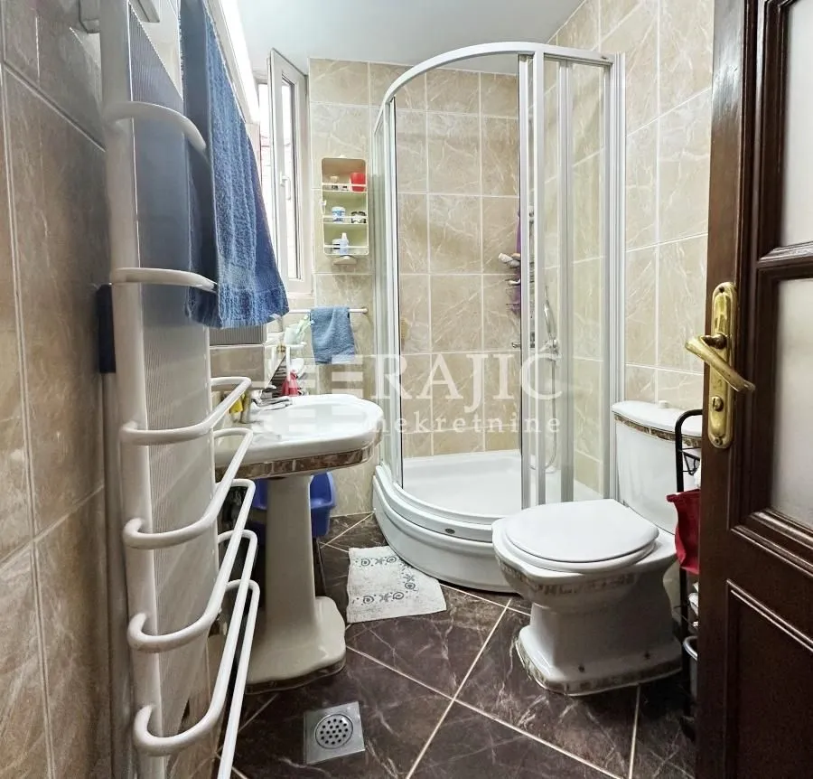 Smaller bathroom with a shower cabin, washbasin, and toilet.