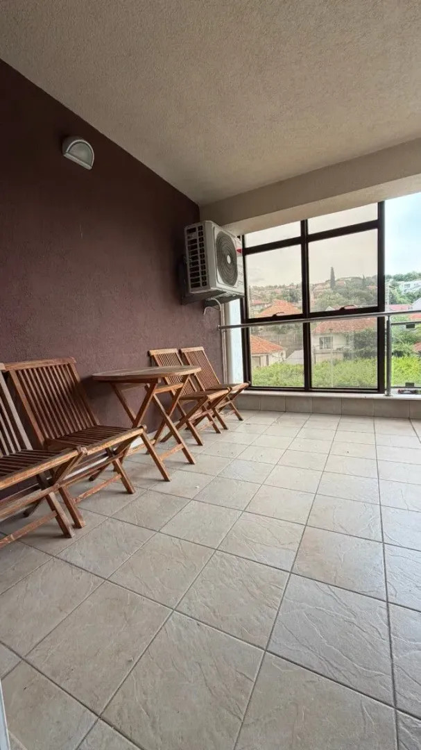 Covered terrace with wooden table and chairs and a view of the neighborhood.
