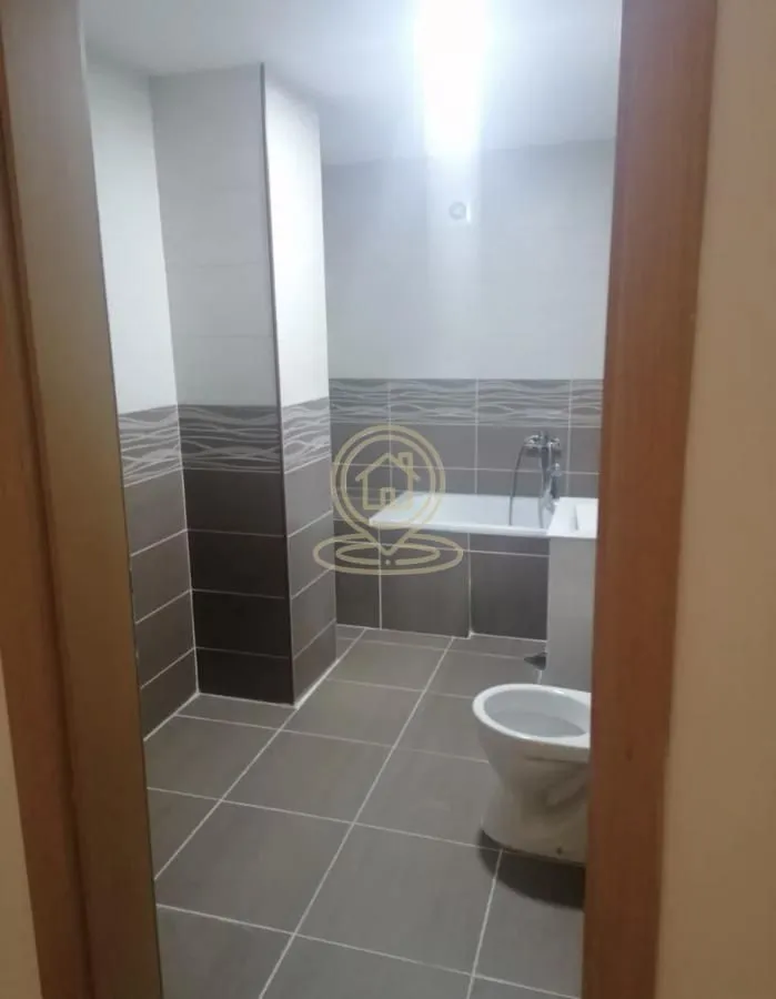 Pogled na kupatilo sa pločicama, kadom i sanitarijama kroz vrata.