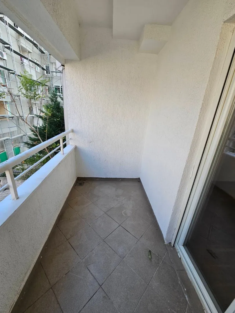Empty covered balcony with ceramic floor tiles and a white railing.
