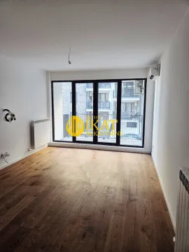 Empty room with wooden flooring, white walls, and large glass doors leading to a balcony. - image 7