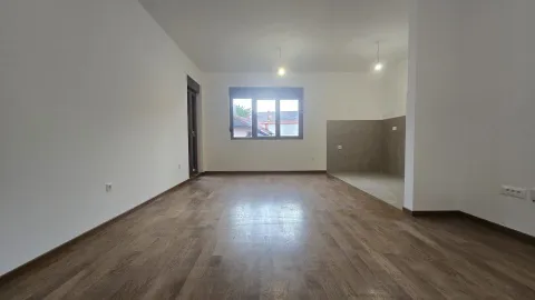 Empty living room with parquet flooring and a designated kitchen area. - image 3