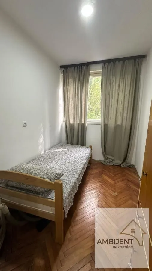 Smaller bedroom with a bed and a window with curtains.
