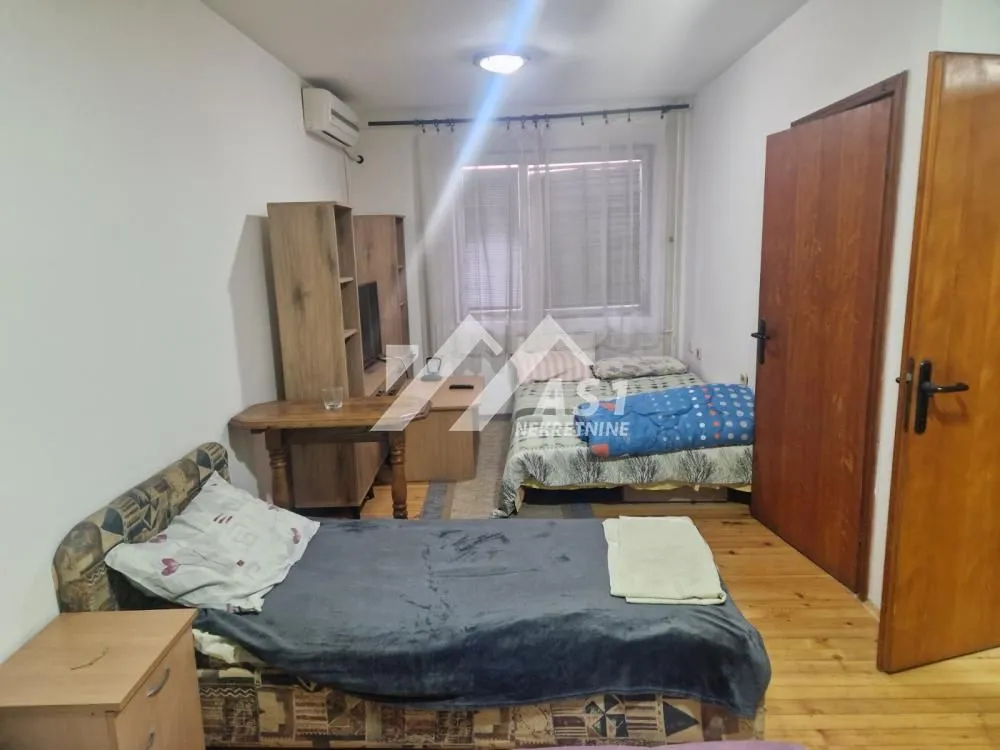Nameštena spavaća soba sa dva kreveta i drvenim ormarima.
