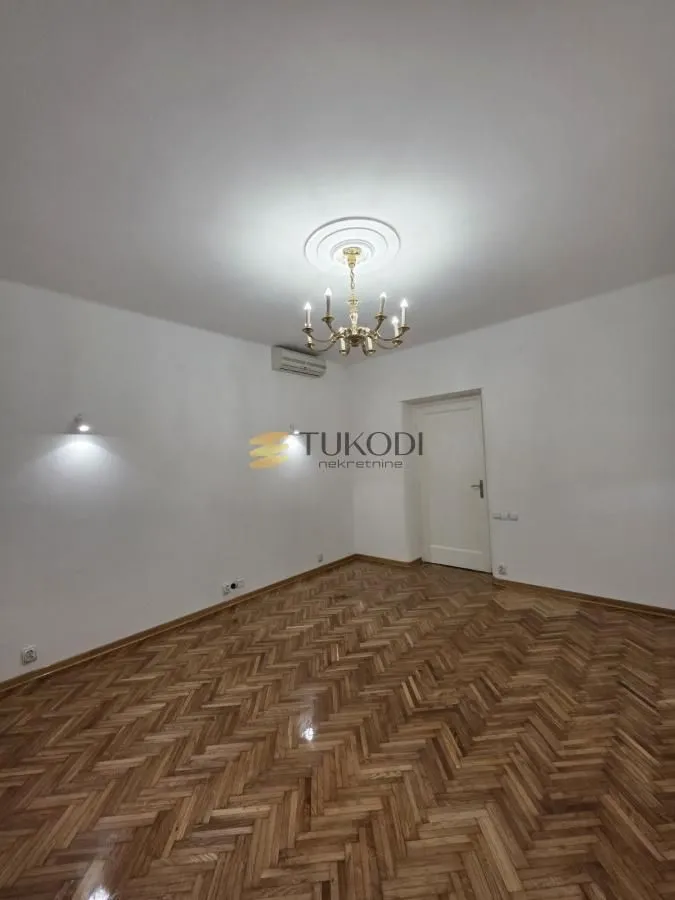 Empty room with parquet flooring and a chandelier on the ceiling.