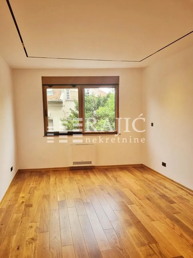 Empty room with wooden flooring and a window.