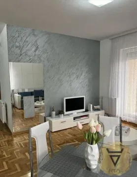 Dnevna soba sa TV komodom, trpezarijskim stolom i ukrasnim zidom. - image 2