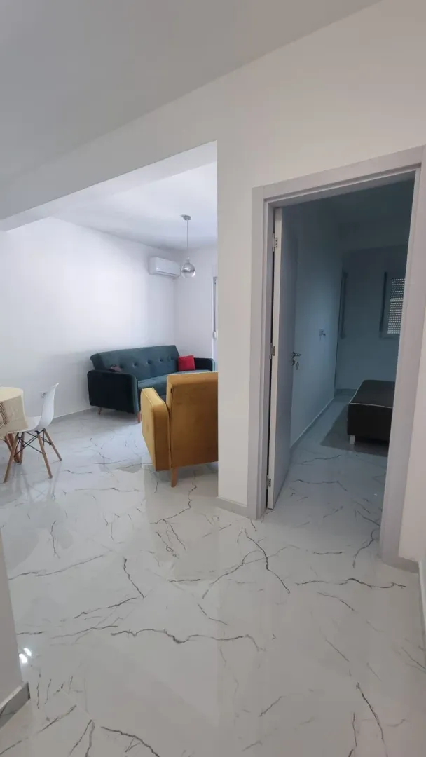 Pogled iz hodnika na svijetli dnevni boravak sa garniturom i trpezarijom.