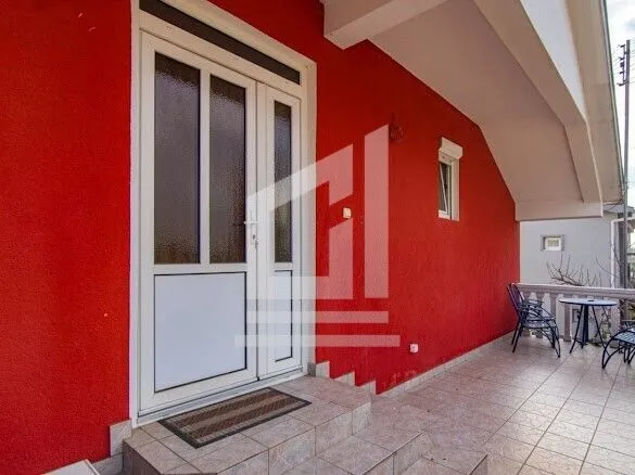 Entrance to the house with a red facade and terrace.