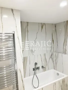 Modern bathroom with white marble-pattern tiles, bathtub, and a chrome towel warmer. - image 11