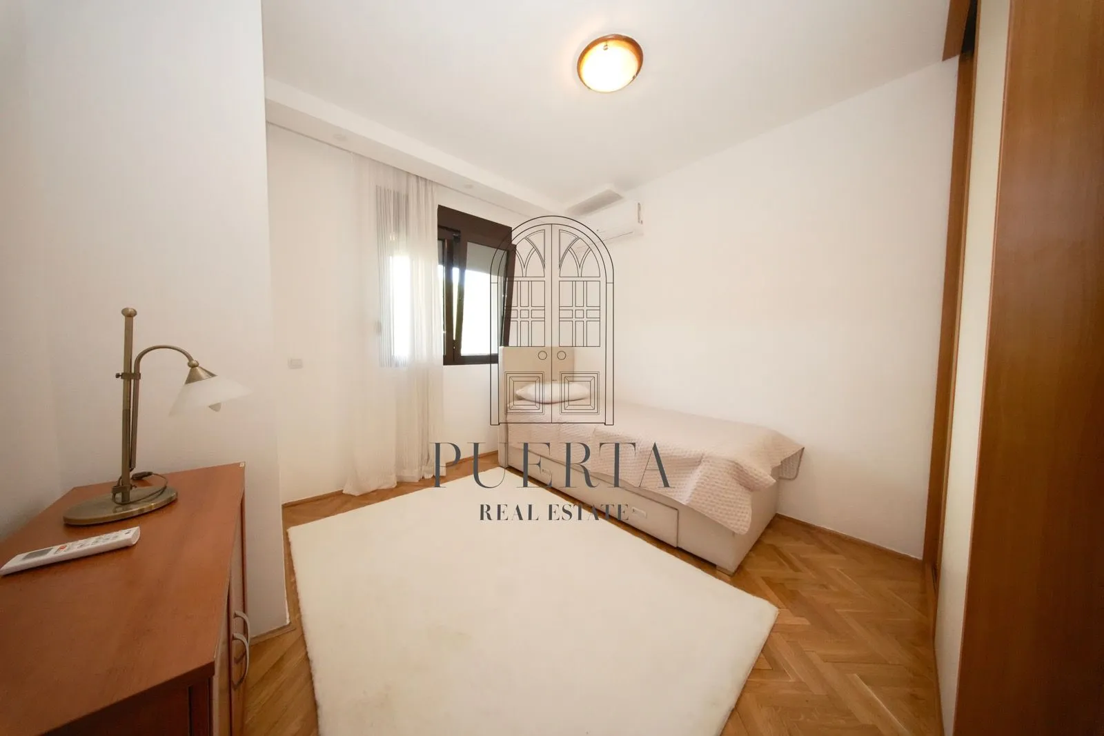 Small bedroom with a bed and wooden flooring.