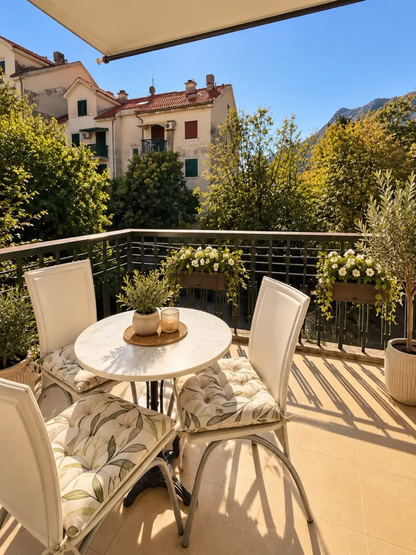Furnished terrace with a table, chairs, and a view of greenery and surrounding buildings.