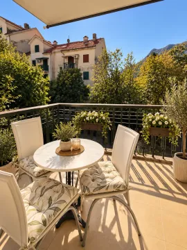 Furnished terrace with a table, chairs, and a view of greenery and surrounding buildings. - image 4