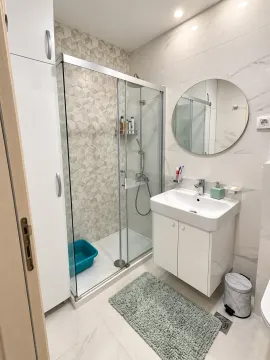 Modern bathroom with a shower cabin, washbasin, and built-in cabinet. - image 4