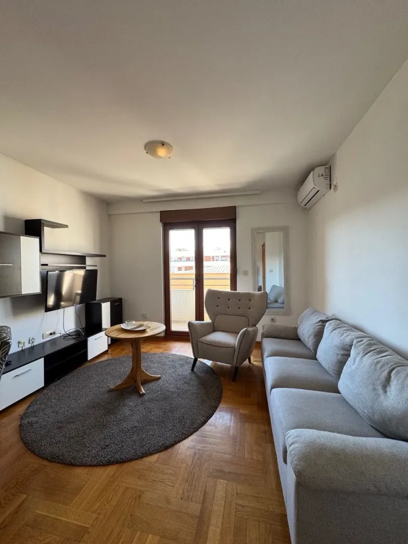 Living room with sofa, armchair, TV cabinet and access to the terrace.