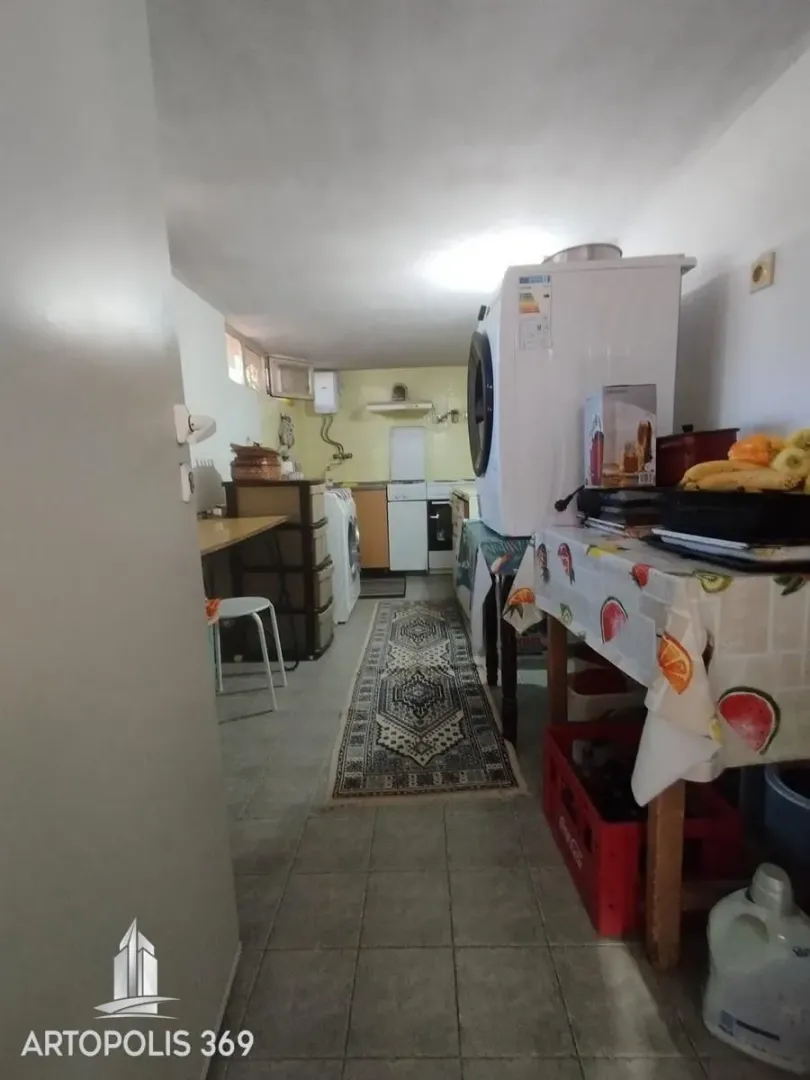 Prikaz dela kuhinje sa stolom i kućnim aparatima.