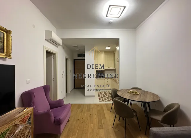 Dnevna soba sa trpezarijom i pogledom prema kuhinji i ulazu.
